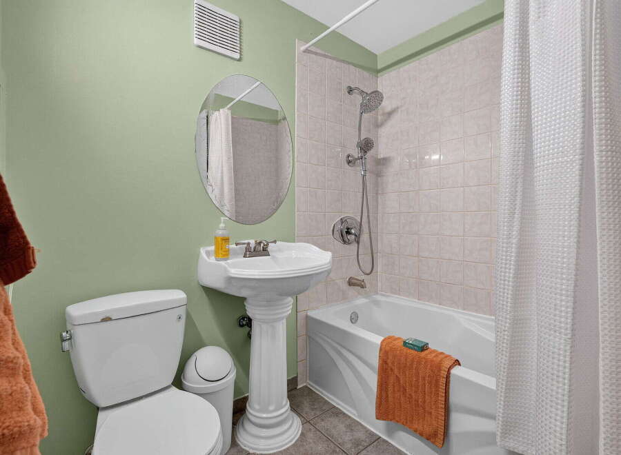 This bathroom features a clean and functional design with a white pedestal sink and a matching toilet.