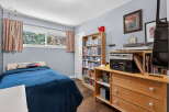 Discover this cozy bedroom featuring a comfortable bed with a deep blue comforter, perfect for relaxation.