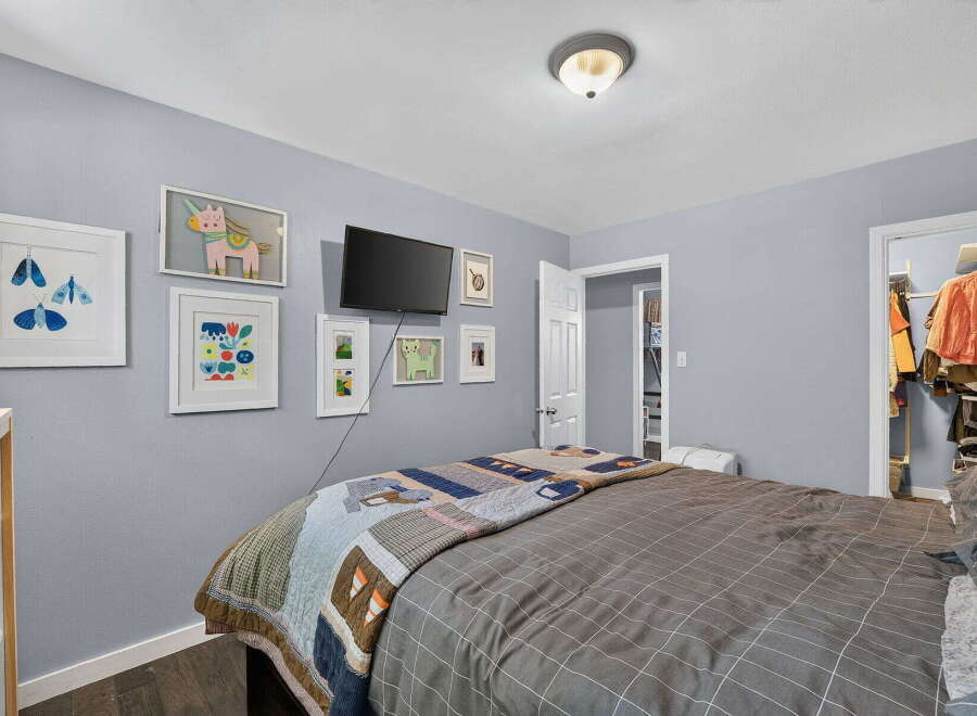 This charming bedroom features a cozy queen-size bed adorned with a colorful patchwork quilt and a modern grey grid duvet.