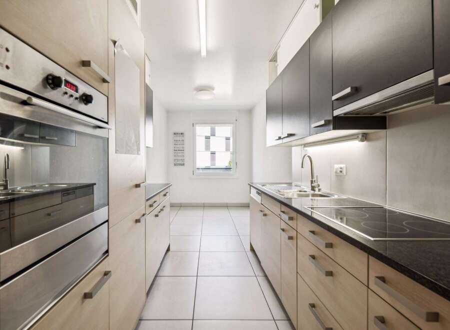 Discover this modern kitchen featuring sleek, light wood cabinetry and dark countertops.
