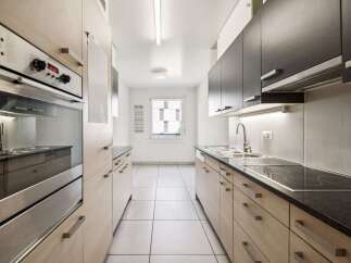 Discover this modern kitchen featuring sleek, light wood cabinetry and dark countertops.