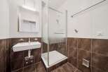 This modern bathroom features a sleek white sink with chrome fixtures, complemented by a frosted glass shower enclosure.