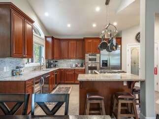 This spacious kitchen boasts rich cherry wood cabinetry, granite countertops, and a large island perfect for entertaining.
