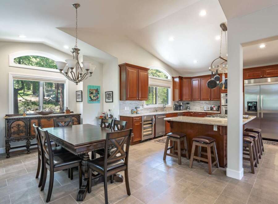 This spacious kitchen and dining area boasts rich cherry wood cabinetry, granite countertops, and a large island perfect for entertaining.