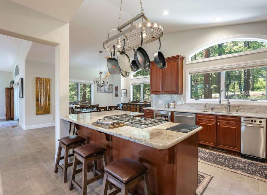 Experience luxury living in this stunning kitchen, featuring a large granite island with a built-in gas range and seating for casual dining.