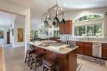 Experience luxury living in this stunning kitchen, featuring a large granite island with a built-in gas range and seating for casual dining.