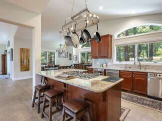 Experience luxury living in this stunning kitchen, featuring a large granite island with a built-in gas range and seating for casual dining.