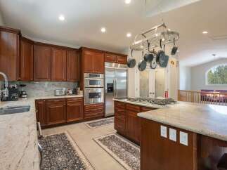 This spacious kitchen boasts rich cherry wood cabinetry and elegant granite countertops, perfect for any home chef.