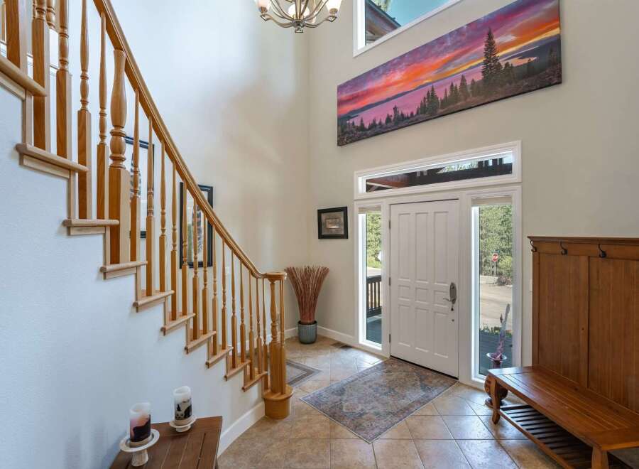 Step into this grand entryway featuring a soaring ceiling and a stunning panoramic landscape artwork above the front door.