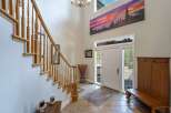 Step into this grand entryway featuring a soaring ceiling and a stunning panoramic landscape artwork above the front door.