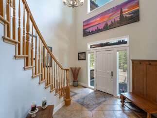 Step into this grand entryway featuring a soaring ceiling and a stunning panoramic landscape artwork above the front door.