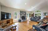 Experience cozy living in this spacious living room, featuring a grand stone fireplace as the centerpiece.