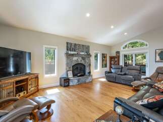 Experience cozy living in this spacious living room, featuring a grand stone fireplace as the centerpiece.