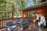 Enjoy the serene mountain setting from this charming cabin's wooden deck, complete with comfortable seating and a grill for outdoor cooking.