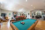 Experience ultimate relaxation and entertainment in this spacious open-concept living area, featuring a cozy stone fireplace and a dedicated game room with a pool table.