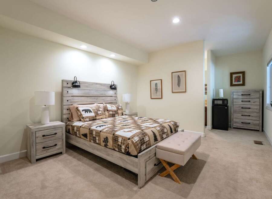 Experience rustic charm in this inviting bedroom, featuring a queen-sized bed with a unique wood-plank headboard and cozy bear-themed bedding.