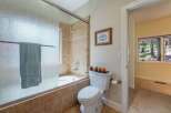 This bathroom features a tiled bathtub and shower area with a frosted glass door and a light blue towel.