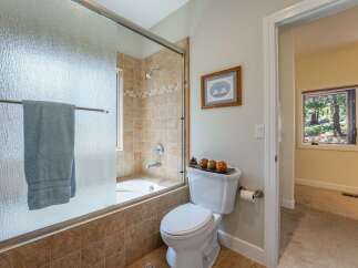This bathroom features a tiled bathtub and shower area with a frosted glass door and a light blue towel.