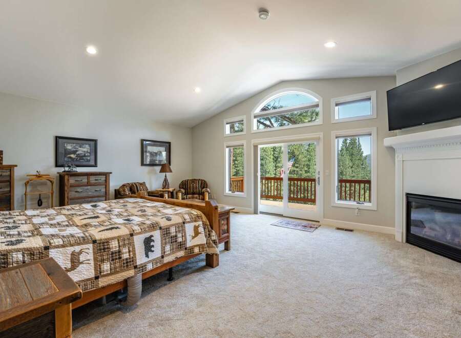 Experience rustic charm in this spacious bedroom, featuring a cozy fireplace and a large TV for entertainment.