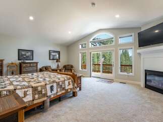 Experience rustic charm in this spacious bedroom, featuring a cozy fireplace and a large TV for entertainment.