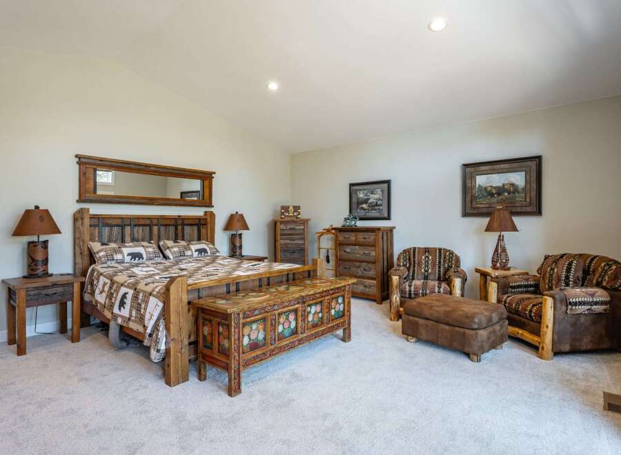 Experience rustic charm in this beautifully appointed bedroom, featuring a king-size bed with a log headboard and cozy bear-themed bedding.