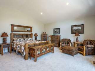 Experience rustic charm in this beautifully appointed bedroom, featuring a king-size bed with a log headboard and cozy bear-themed bedding.