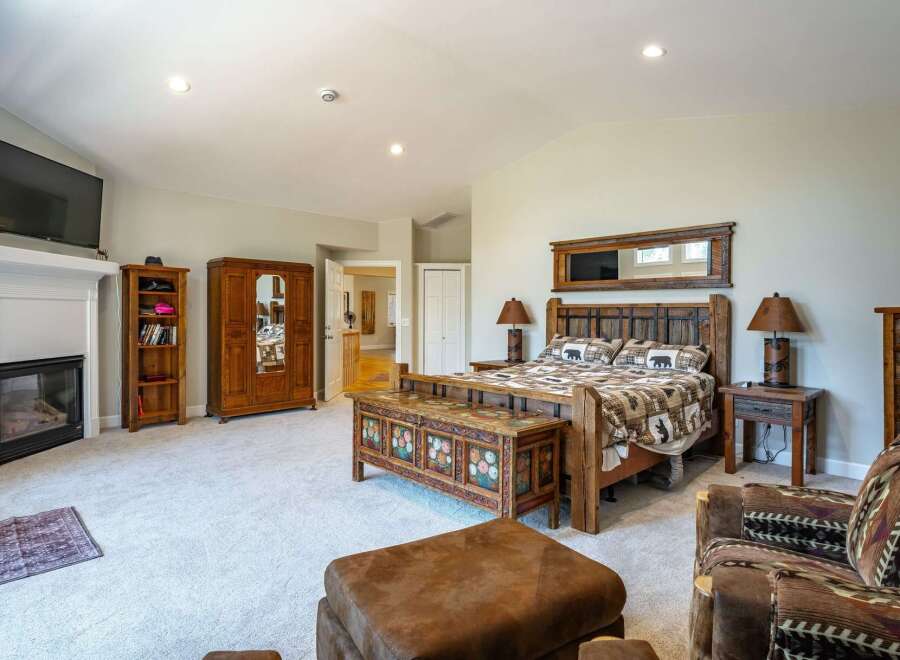 Experience rustic charm in this spacious bedroom, featuring a cozy fireplace and a large wooden armoire for ample storage.