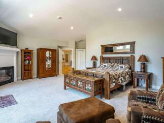 Experience rustic charm in this spacious bedroom, featuring a cozy fireplace and a large wooden armoire for ample storage.