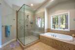 Experience luxury in this spacious bathroom, featuring a stunning glass-enclosed walk-in shower with multiple showerheads and a built-in bench.