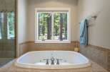 Indulge in relaxation in this luxurious bathroom featuring a spacious soaking tub with a scenic forest view.