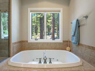 Indulge in relaxation in this luxurious bathroom featuring a spacious soaking tub with a scenic forest view.