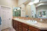 This spacious bathroom features a double vanity with elegant wood cabinetry and a tiled backsplash.
