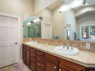 This spacious bathroom features a double vanity with elegant wood cabinetry and a tiled backsplash.