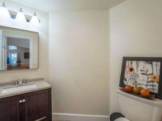 This bathroom features a modern vanity with a granite countertop and a sleek faucet, complemented by a large vanity mirror with an attached light fixture.