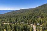 Experience the serene beauty of this mountain retreat, nestled amidst a dense forest with breathtaking views of a distant lake and snow-capped mountains.