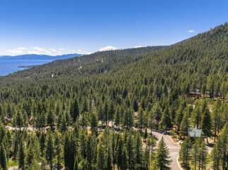 Experience the serene beauty of this mountain retreat, nestled amidst a dense forest with breathtaking views of a distant lake and snow-capped mountains.