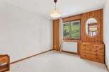 Experience rustic charm in this inviting bedroom, featuring warm wood paneling and a large window with scenic mountain views.