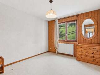 Experience rustic charm in this inviting bedroom, featuring warm wood paneling and a large window with scenic mountain views.