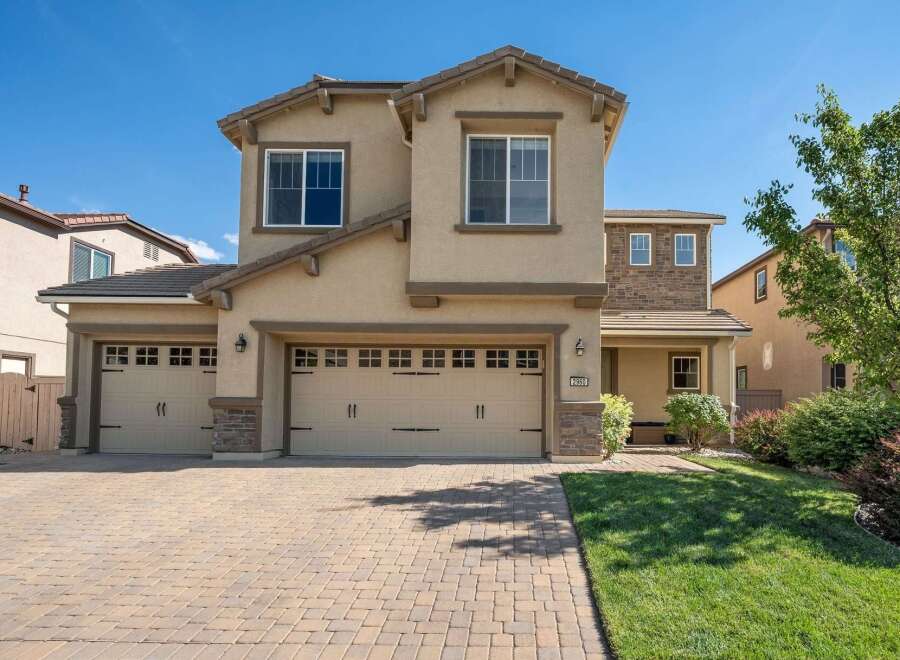 This stunning two-story home features a welcoming facade with a three-car garage and a charming covered porch.