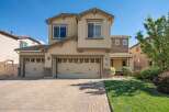 This stunning two-story home features a welcoming facade with a three-car garage and a charming covered porch.