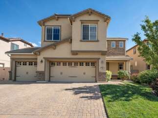 This stunning two-story home features a welcoming facade with a three-car garage and a charming covered porch.