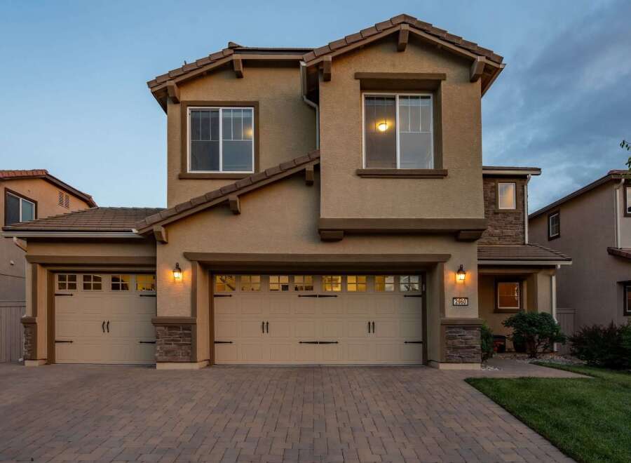 This stunning two-story home features a welcoming facade with a three-car garage and elegant stone accents.