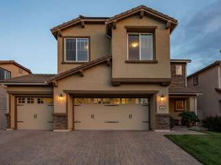 This stunning two-story home features a welcoming facade with a three-car garage and elegant stone accents.