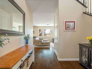 Step into this inviting entryway featuring a spacious hallway with a large decorative mirror and a charming wooden console table with ample storage.
