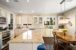 This spacious kitchen boasts elegant cream cabinetry and a large granite island, perfect for meal preparation and casual dining.