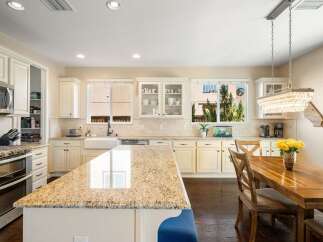 This spacious kitchen boasts elegant cream cabinetry and a large granite island, perfect for meal preparation and casual dining.