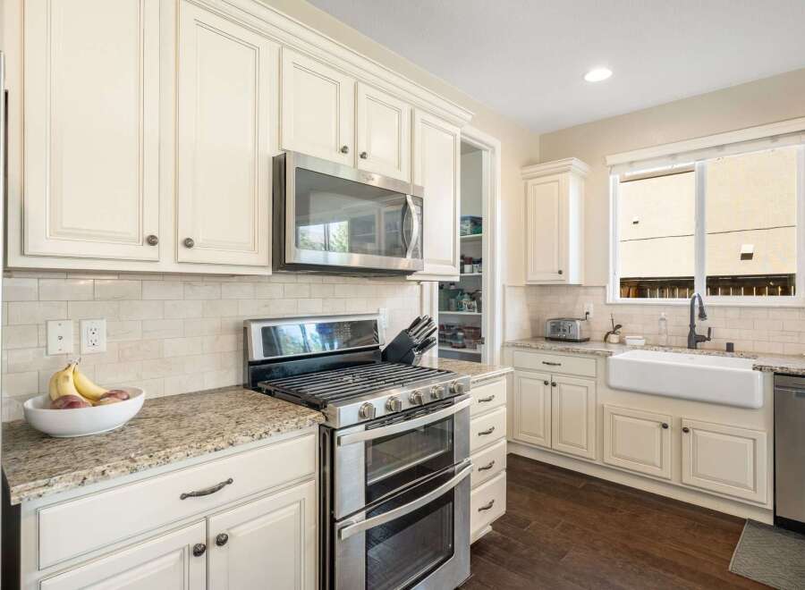 This spacious kitchen boasts elegant cream-colored cabinetry, complemented by a sleek stainless steel double oven and microwave.