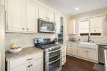This spacious kitchen boasts elegant cream-colored cabinetry, complemented by a sleek stainless steel double oven and microwave.