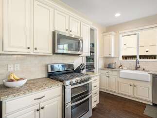 This spacious kitchen boasts elegant cream-colored cabinetry, complemented by a sleek stainless steel double oven and microwave.