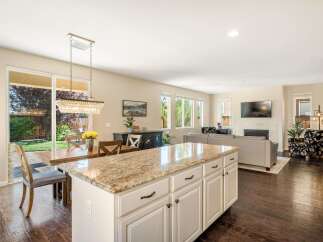 Experience open-concept living in this stunning home, featuring a spacious kitchen island with granite countertops perfect for entertaining.